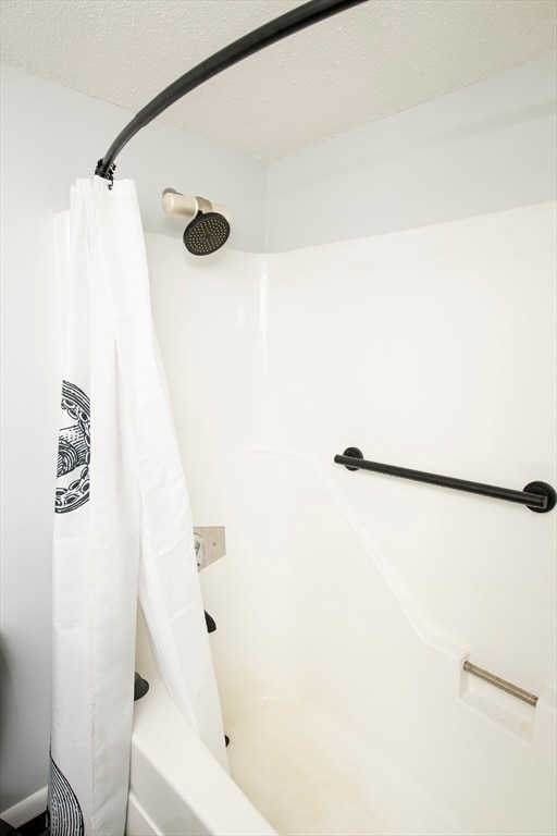 bathroom featuring shower / bath combination with curtain and a textured ceiling