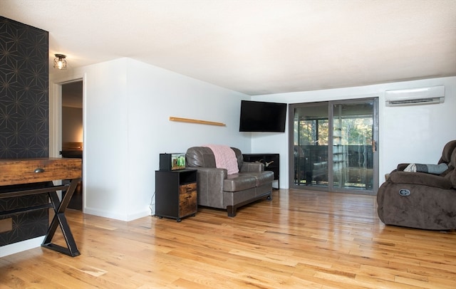 living room with a wall mounted AC and light hardwood / wood-style flooring