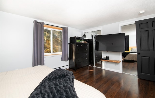 bedroom featuring a closet, dark hardwood / wood-style floors, baseboard heating, and a textured ceiling