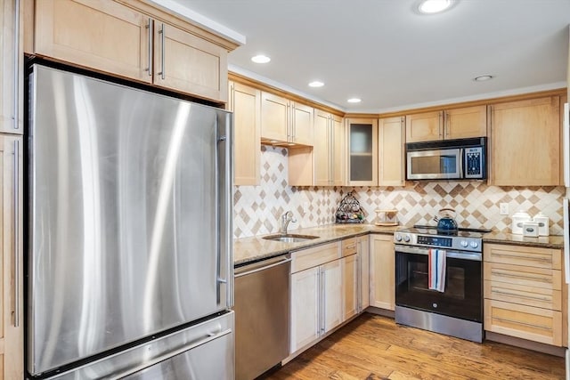 kitchen with light brown cabinets, appliances with stainless steel finishes, and a sink
