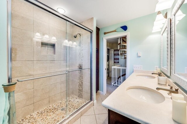 full bath featuring a sink, a shower stall, tile patterned flooring, and double vanity