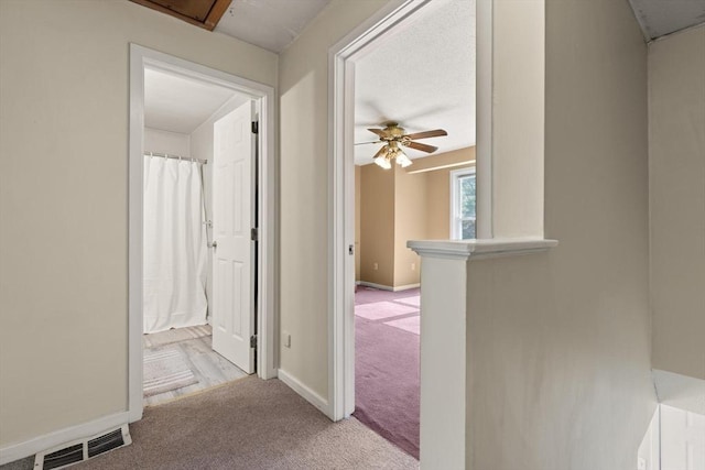 hall featuring baseboards, carpet, attic access, and visible vents