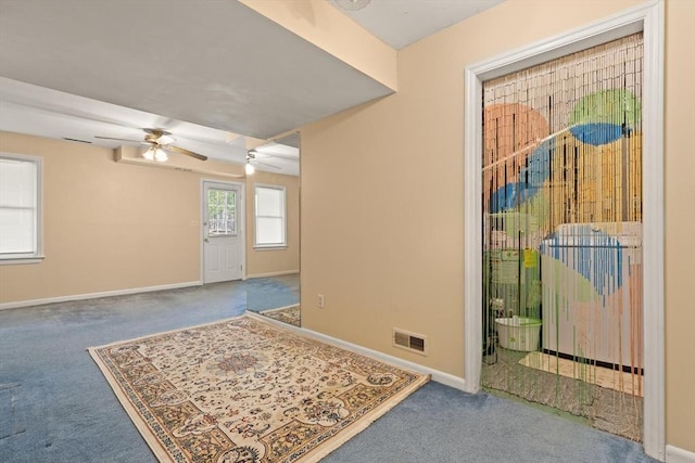 unfurnished room featuring carpet floors, baseboards, a ceiling fan, and visible vents