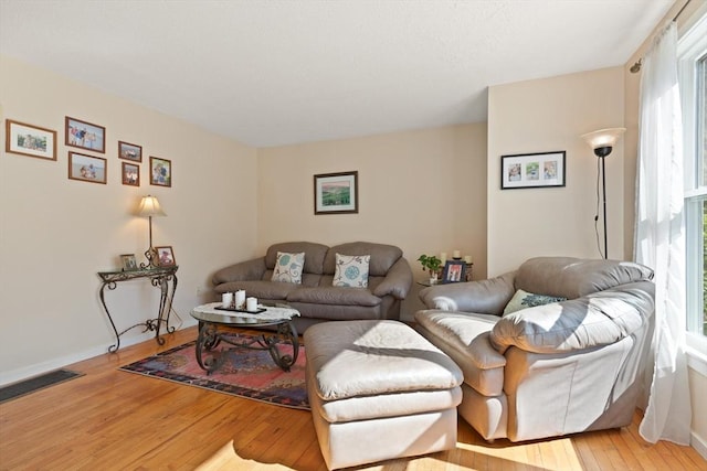 living area with baseboards, visible vents, and hardwood / wood-style floors