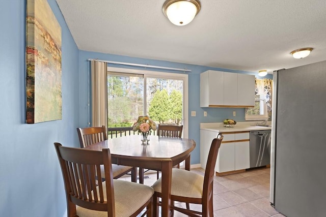 dining room featuring baseboards, a textured ceiling, and light tile patterned floors