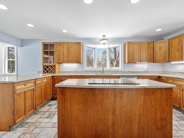 kitchen with stone tile floors, brown cabinets, a center island, a sink, and recessed lighting