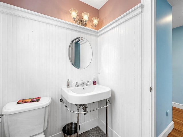 half bath with a sink, toilet, and baseboards