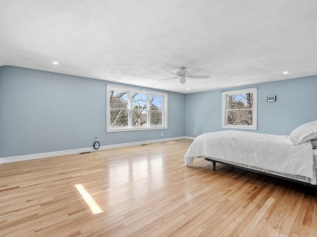 bedroom with baseboards, ceiling fan, visible vents, and light wood finished floors