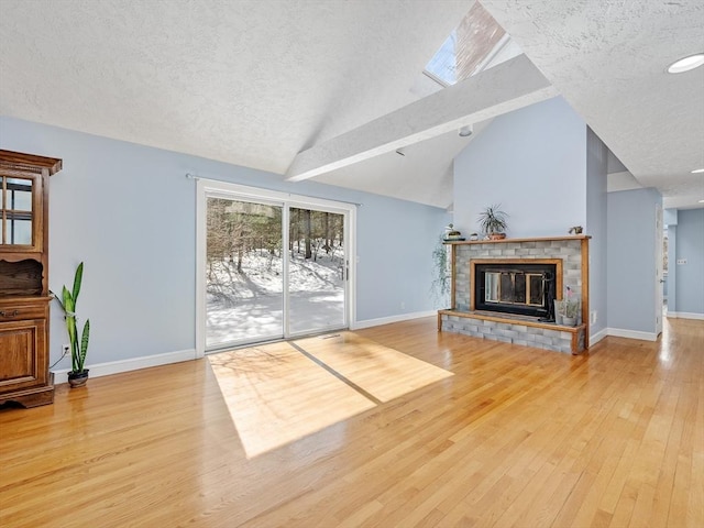 living area with light wood-style flooring, a fireplace, baseboards, and a textured ceiling