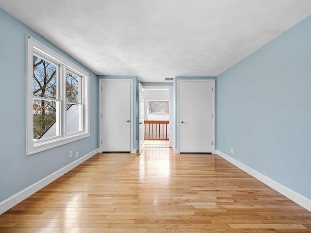 unfurnished room with baseboards, visible vents, and light wood finished floors