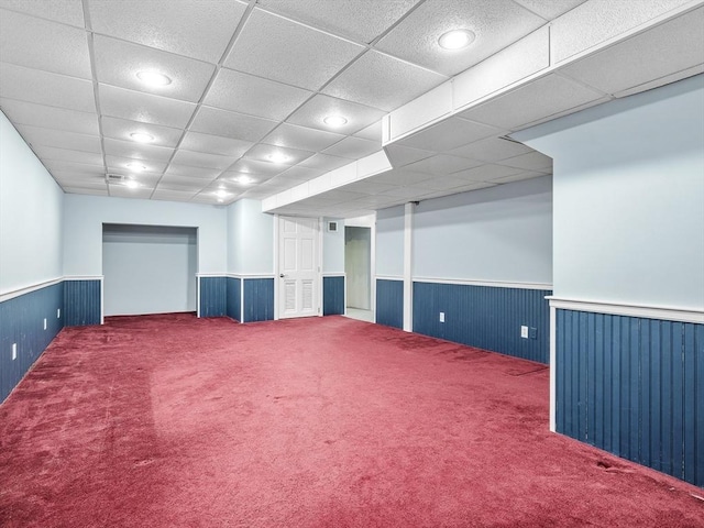 carpeted empty room with a drop ceiling, wood walls, wainscoting, and recessed lighting