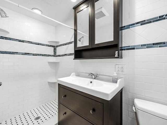 bathroom with tile walls, backsplash, toilet, a stall shower, and vanity