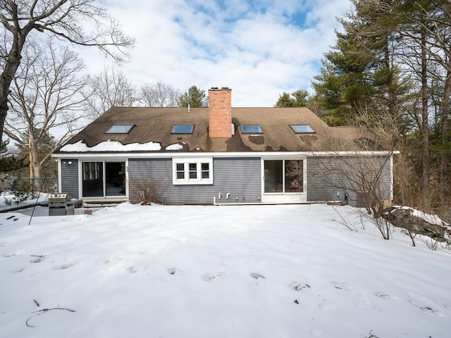 snow covered back of property with a chimney