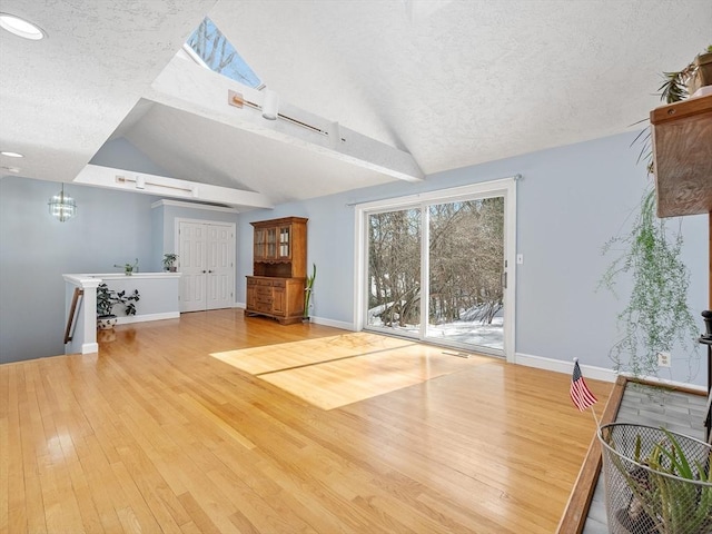 unfurnished living room featuring light wood-type flooring, lofted ceiling, and a textured ceiling