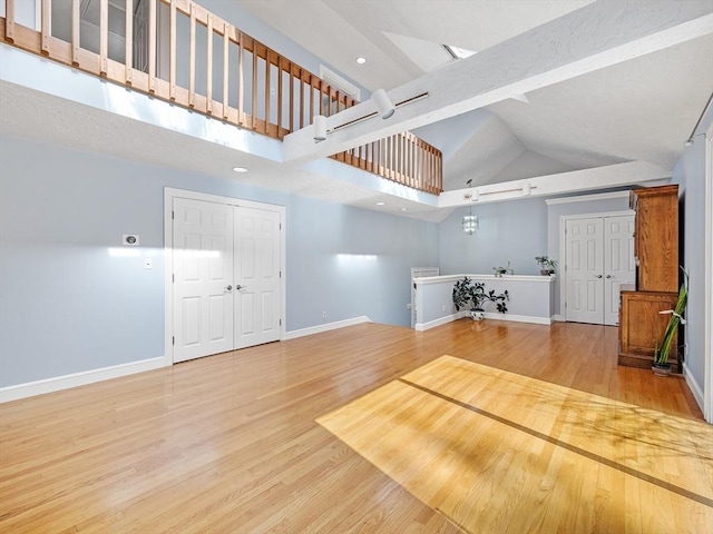 interior space with high vaulted ceiling, beam ceiling, baseboards, and wood finished floors