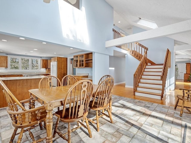 dining space featuring recessed lighting, baseboards, stairway, and a high ceiling