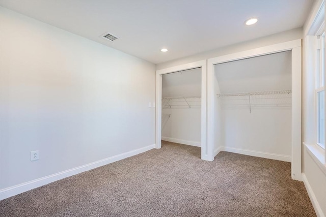 unfurnished bedroom with multiple closets and carpet flooring