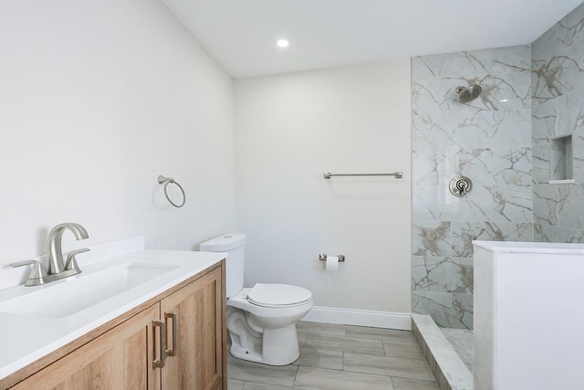 bathroom featuring toilet, vanity, and a tile shower