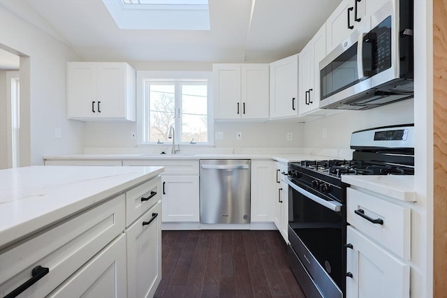 kitchen with appliances with stainless steel finishes, sink, dark wood-type flooring, white cabinetry, and light stone countertops