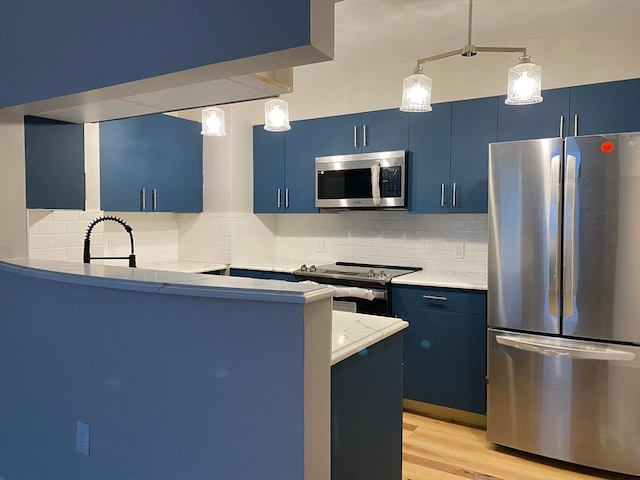 kitchen featuring blue cabinetry, pendant lighting, backsplash, and stainless steel appliances