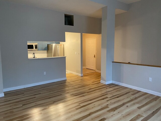 unfurnished room featuring a high ceiling and light wood-type flooring