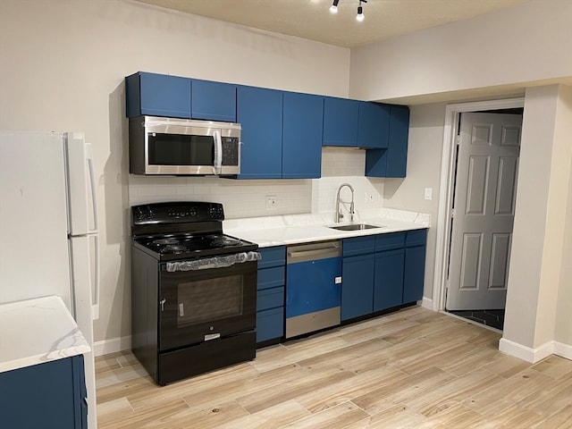 kitchen with tasteful backsplash, stainless steel appliances, light stone countertops, sink, and blue cabinetry