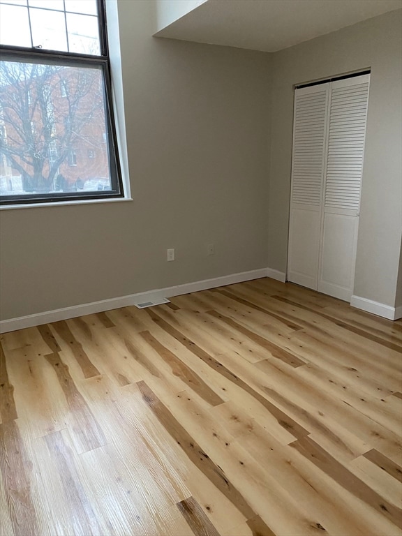 unfurnished bedroom with light wood-type flooring and a closet