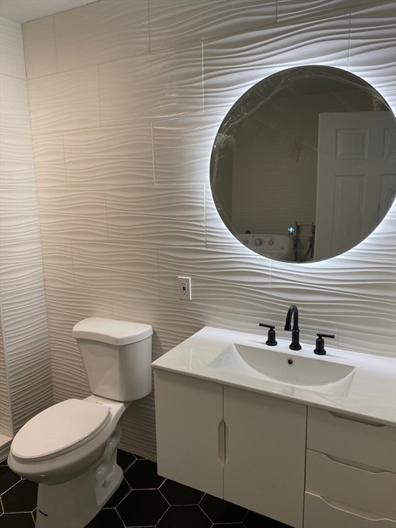 bathroom featuring toilet, tile flooring, vanity, backsplash, and tile walls