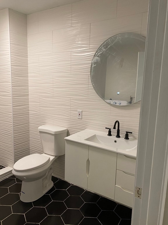 bathroom featuring tile walls, tile floors, toilet, and vanity