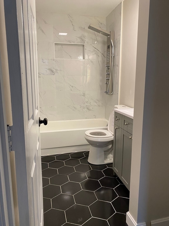 full bathroom with tiled shower / bath combo, vanity, tile flooring, and toilet