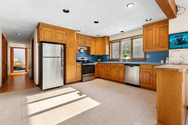 kitchen featuring tasteful backsplash, sink, light tile patterned flooring, and appliances with stainless steel finishes