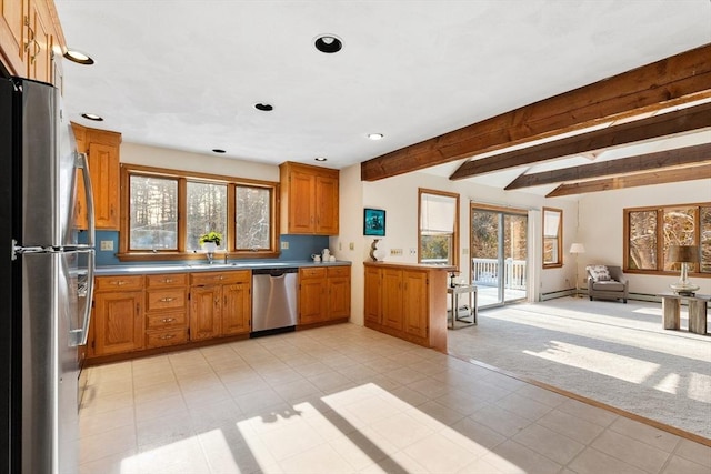 kitchen with stainless steel appliances, beam ceiling, light carpet, and a wealth of natural light