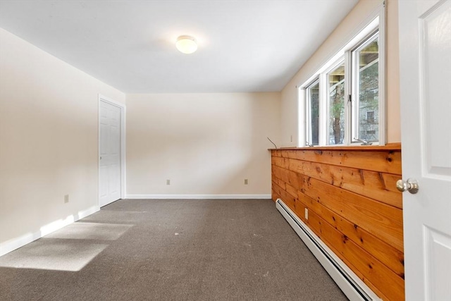 unfurnished room featuring dark carpet and baseboard heating