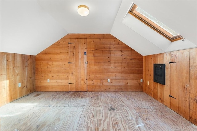 bonus room with light hardwood / wood-style flooring, wooden walls, and vaulted ceiling with skylight