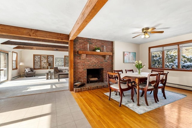 tiled dining space featuring ceiling fan, a fireplace, and beamed ceiling