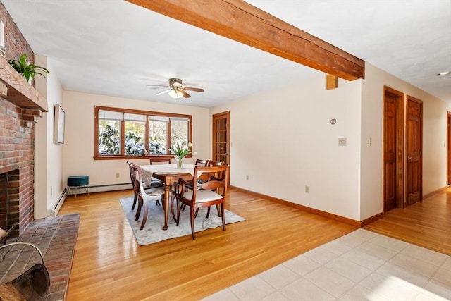 dining room featuring beam ceiling, a fireplace, light hardwood / wood-style floors, and ceiling fan