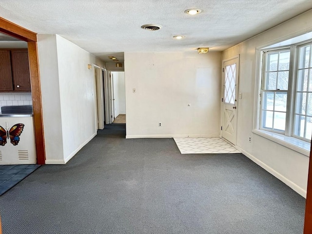 spare room featuring a textured ceiling, carpet flooring, visible vents, and baseboards