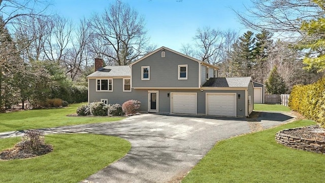 tri-level home featuring driveway, a chimney, fence, and a front yard
