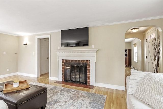 15 Maple St, Salem, MA 01970 - living area with wood finished floors, arched walkways, ornamental molding, a brick fireplace, and a baseboard radiator