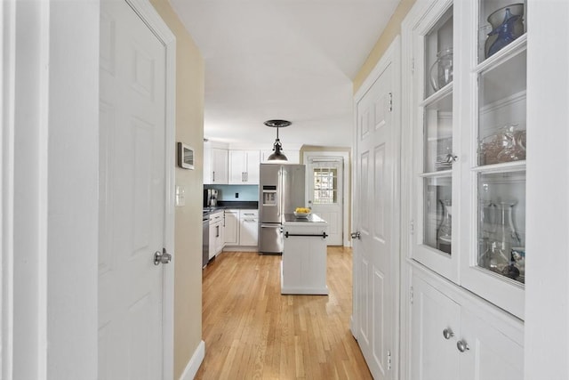 15 Maple St, Salem, MA 01970 - kitchen with appliances with stainless steel finishes, white cabinetry, light wood-style flooring, pendant lighting, and a center island