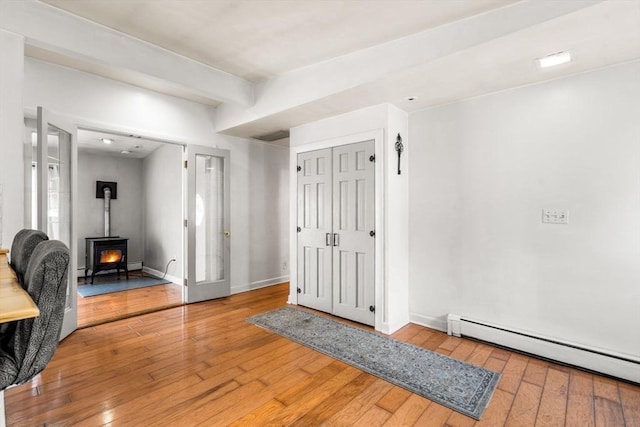 entrance foyer with hardwood / wood-style flooring, a wood stove, baseboards, and baseboard heating