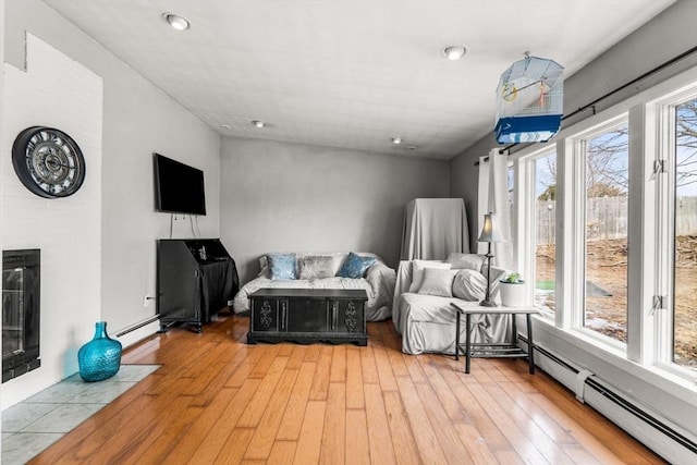 interior space with light wood finished floors, a fireplace, and a baseboard heating unit