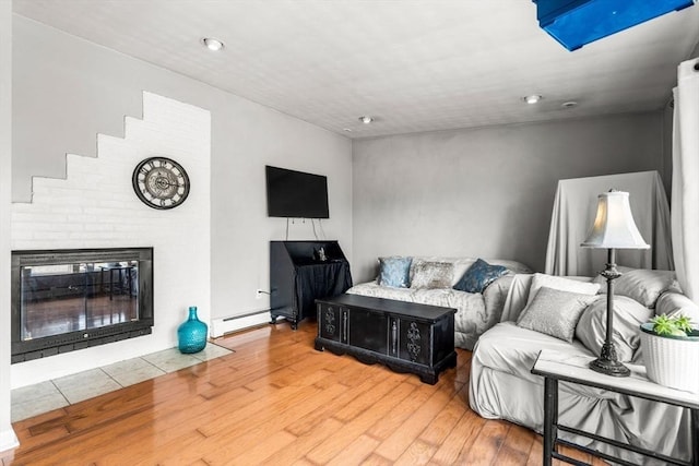 living room featuring a fireplace, wood finished floors, and a baseboard radiator