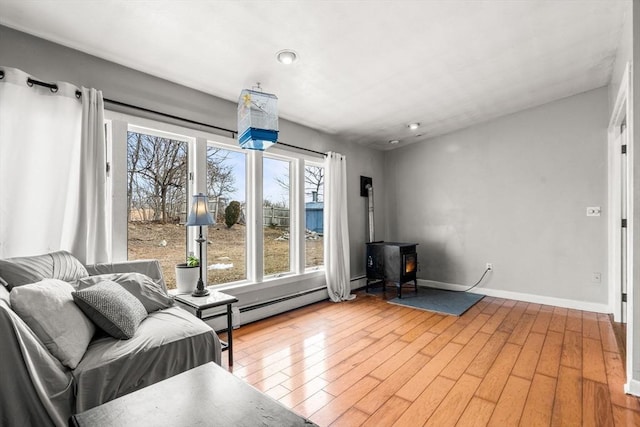 living room with a wood stove, wood finished floors, baseboards, and baseboard heating