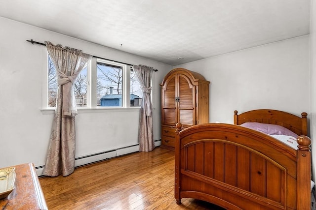 bedroom with a baseboard radiator and light wood-style flooring