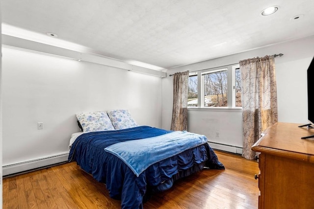 bedroom featuring wood-type flooring and a baseboard radiator