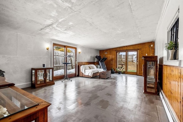 bedroom with a baseboard radiator, wooden walls, wood finished floors, and access to outside