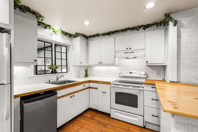 kitchen featuring electric stove, under cabinet range hood, a sink, stainless steel fridge, and dishwasher