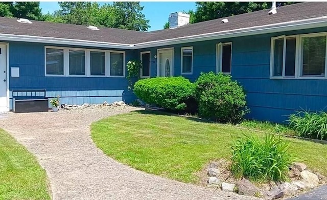 property entrance featuring a lawn and a chimney