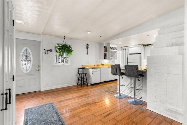 entrance foyer featuring light wood-type flooring, baseboards, and vaulted ceiling